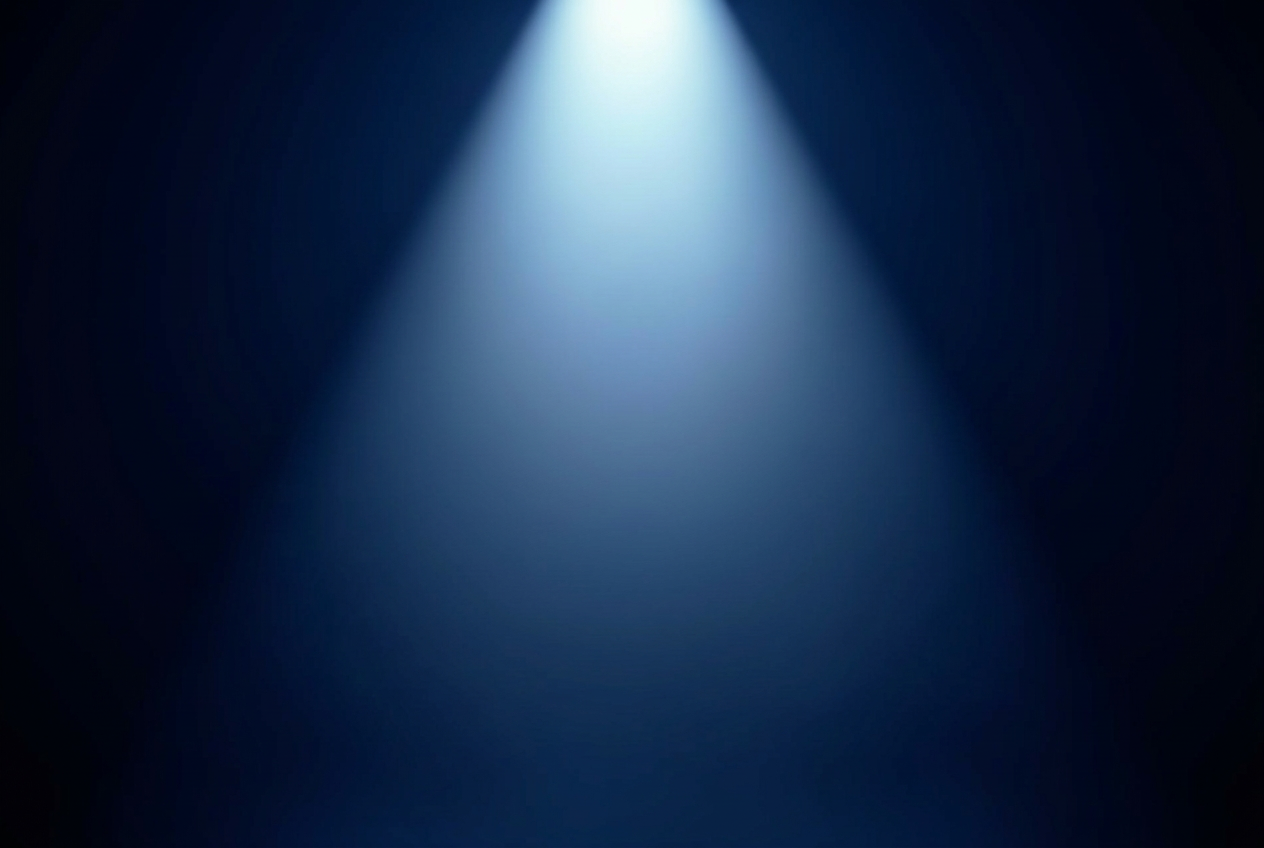 A single soft spotlight beam descending through deep blue darkness